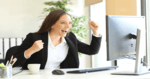 woman seated in front of her computer monitor, looking very excited with what she is seeing